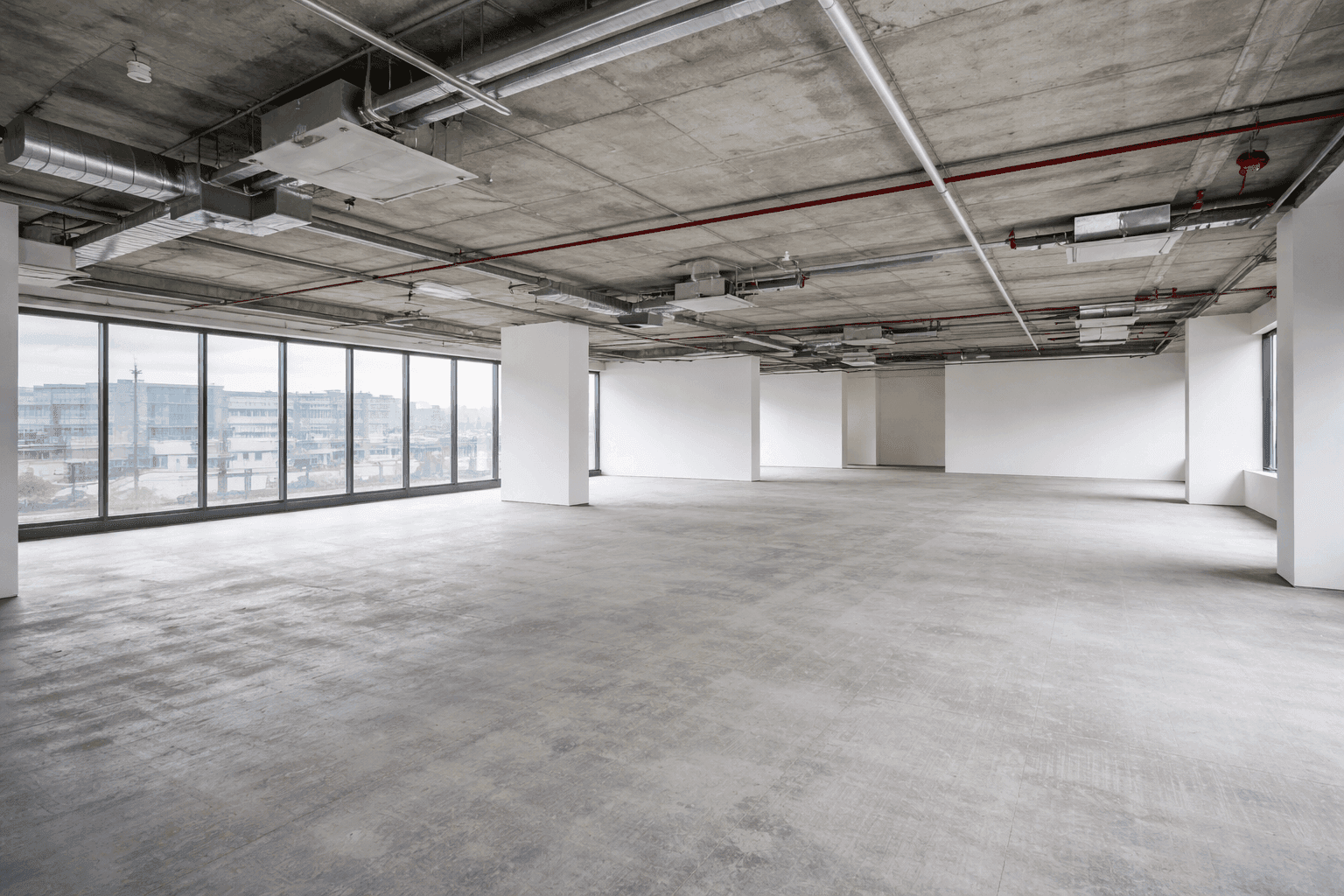 Empty shell commercial space ready for a full fitout - bare concrete floor with exposed ceiling services
